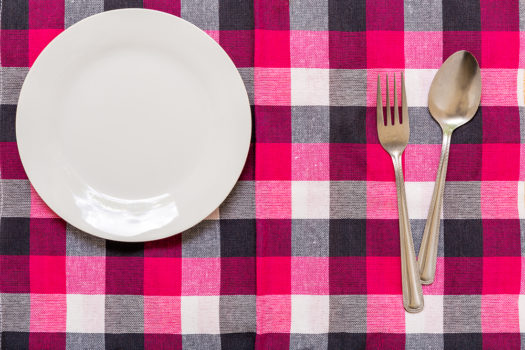 Empty plate with spoon and fork on table background.